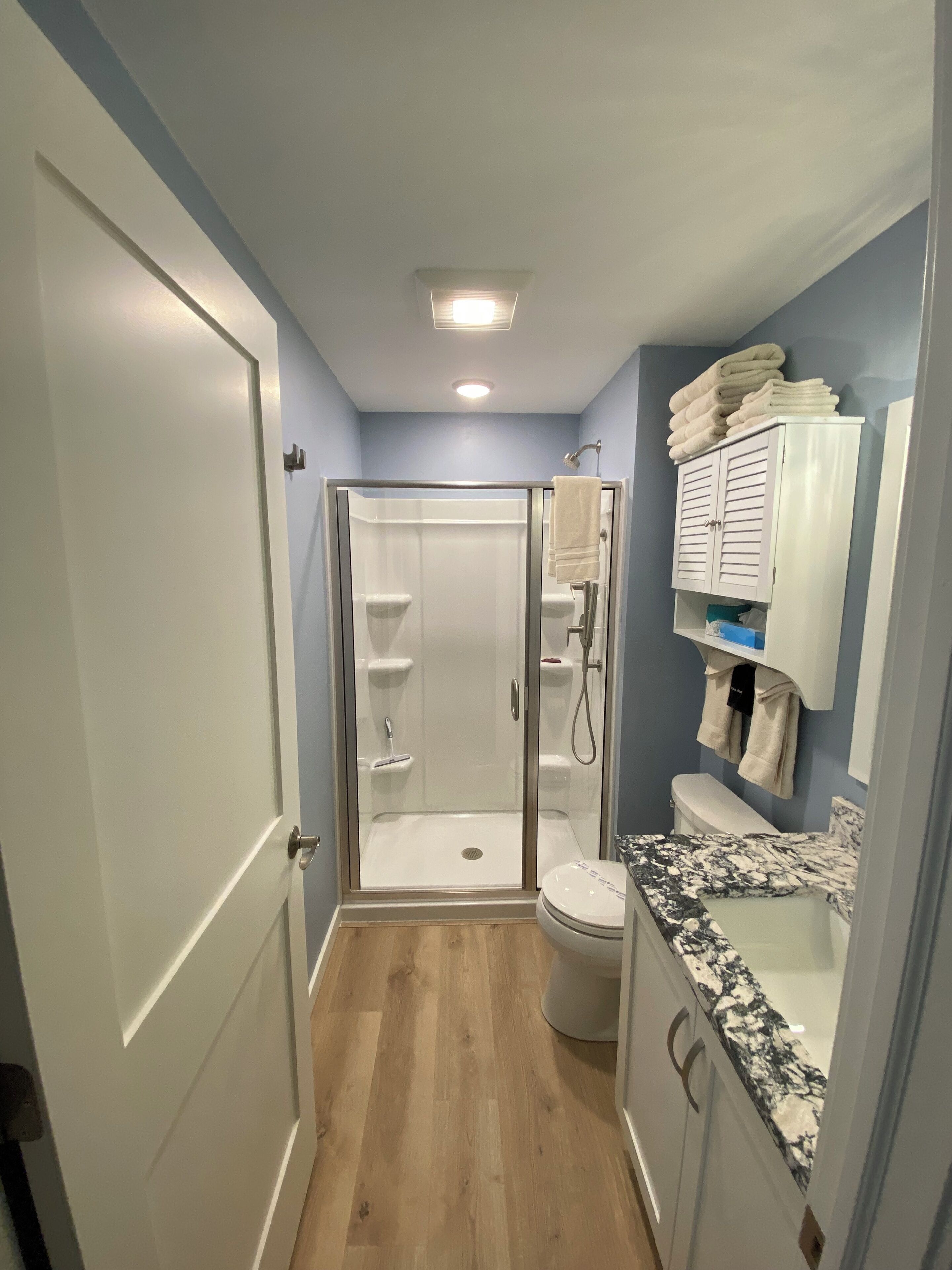 A bathroom with a walk-in shower, a toilet, and a sink with a marble countertop.
