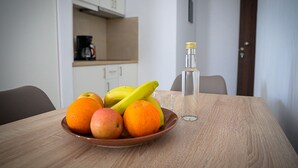 A dining table with a fruit bowl containing apples and oranges, a glass of water, and a bottle of water.