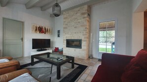Ein Wohnzimmer mit Fernseher, Steinwand, Kamin und einem großen Fenster.