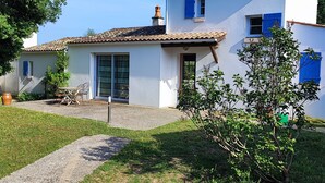 Ein zweistöckiges Haus mit Ziegeldach, einer Haustür und einer kleinen Terrasse.