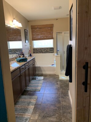 A bathroom with a shower, a bathtub, a vanity with a countertop, and a window with blinds. - Spacious house w/pool and hot tub. Plenty of room to entertain! (Queen Creek)