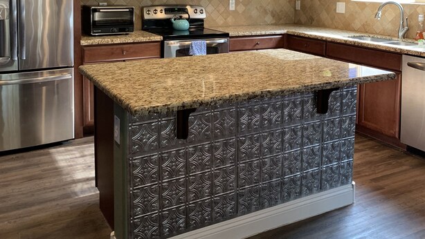 Una cucina moderna con mobili in legno, elettrodomestici in acciaio inossidabile e un'isola con piano in granito.
