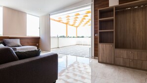 Una sala moderna con un sofá, un mueble de madera y un ventanal que da a un espacio exterior.