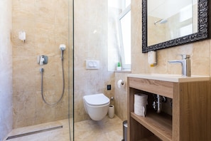 A modern bathroom with a glass shower enclosure, a toilet, and a wooden vanity with a mirror. - B&B Giardin (Zadar)