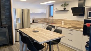 A modern kitchen with a wooden dining table, black chairs, and a built-in oven.