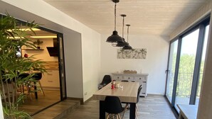 A modern kitchen with a wooden countertop, black chairs, and pendant lights.