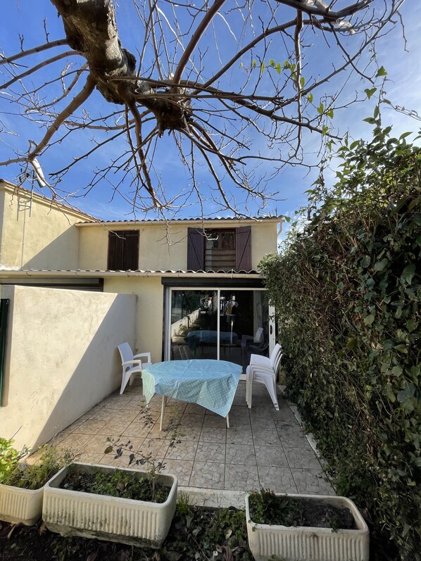A patio with a table and chairs, a sliding glass door, and a small garden area with planters.