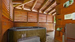 Innenansicht einer Holzhütte mit Whirlpool, Holzwänden und einem Schild, das davor warnt, auf die Whirlpool-Abdeckung zu steigen.