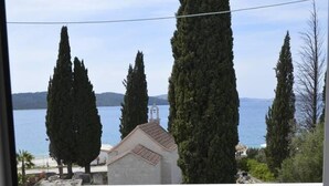 Un balcon donnant sur un plan d’eau, de grands arbres et un bâtiment doté d’un clocher.