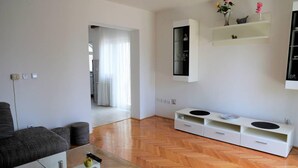 Un salon moderne avec un canapé, une table basse en verre et un meuble de rangement blanc doté d’étagères.