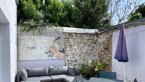 Eine Terrasse mit einer Steinmauer, einem grauen Sofa, einem Tisch und Stühlen.