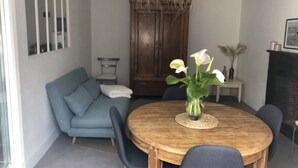 Ein Essbereich mit einem runden Holztisch, einer blauen Couch und einer Vase mit Blumen.