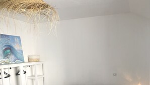 Ein Schlafzimmer mit einem großen Bett, einer weißen Kommode, einem Gemälde und einem kleinen Nachttisch mit Lampe.