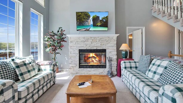 A living room with a fireplace, two sofas, a coffee table, and a TV mounted above the fireplace. - Lakefront Family Retreat | Sleeps 10+ | Pet-Friendly | Swim & Fish Off the Dock (Sunrise Beach)