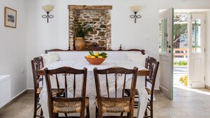 A dining area with a stone wall, a table with a white tablecloth, and a bowl of lemons and limes.