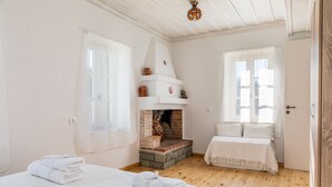 A cozy room with a fireplace, two beds, and a door.