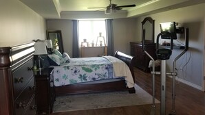 Un dormitorio con cama, cómoda, espejo y equipo de ejercicio.