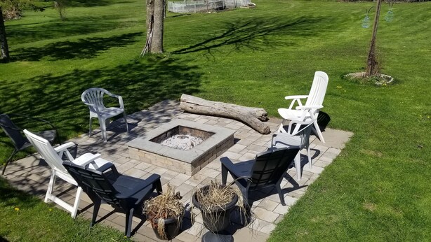 Un patio al aire libre con una fogata, rodeado de sillas y macetas.