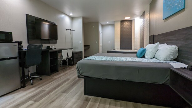 A modern hotel room with a bed, desk, chair, and a flat-screen TV. - Crystal Inn Jacinto City (Houston)