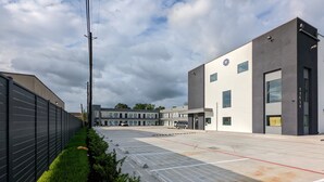 A parking lot with a modern building in the background. - Crystal Inn Jacinto City (Houston)