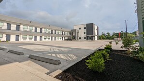 A modern building with a flat roof, multiple windows, and a parking lot. - Crystal Inn Jacinto City (Houston)