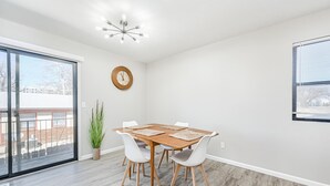 A dining area with a wooden table and white chairs, a potted plant, and a wall clock. - Cozy 2BD Near Hospital (Wichita)