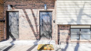A brick building with two dark-colored doors and a small window with blinds. - Cozy 2BD Near Hospital (Wichita)