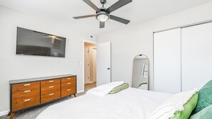A bedroom with a bed, a dresser, a ceiling fan, a TV, and a wardrobe. - Cozy 2BD Near Hospital (Wichita)