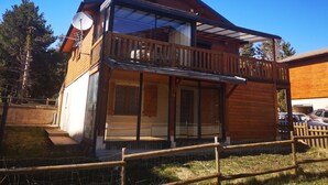 Une maison en bois à deux étages, dotée d’un balcon, de grandes fenêtres et d’une antenne parabolique.