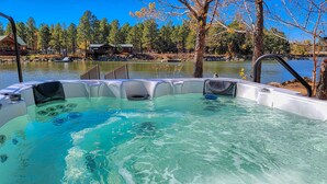Ein Whirlpool mit klarem Wasser, umgeben von Bäumen und einem Haus im Hintergrund.