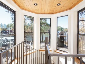 A modern interior with large windows, a wooden ceiling, and a view of a lake and trees.
