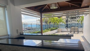 Cocina moderna con una isla grande, comedor con sillas y vista a una obra en construcción.
