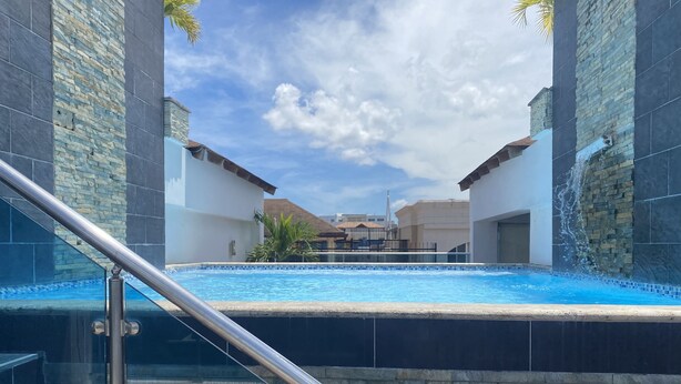 Una piscina con barandilla de vidrio, rodeada de muros de piedra y un cielo despejado.