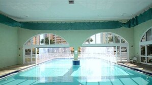 Una piscina interior amb finestres d'arc i vista a edificis a l'exterior.