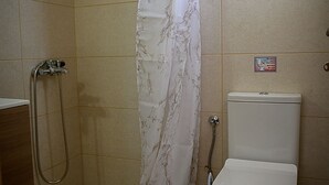 Een kleine badkamer met een douche, toilet en een handdroger.