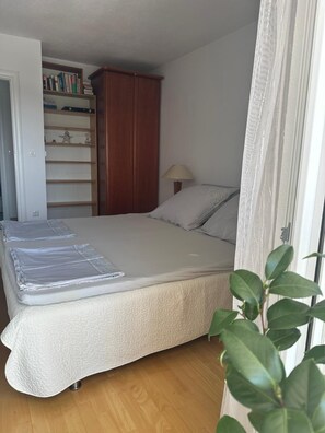 Makuuhuone, jossa on sänky, vaatekaappi, lamppu ja kasvi.