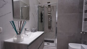 A modern bathroom with a glass-enclosed shower, a white sink, and a toilet. - Puglia in love (Margherita di Savoia)