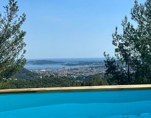 Una piscina amb vistes a un paisatge urbà costaner i a les colines.