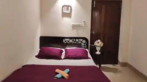 A bedroom with a bed, a nightstand, a wall-mounted light, and a door. - 3 Bedroom Apartment near Dhanmondi & Panthpath (Dhaka)