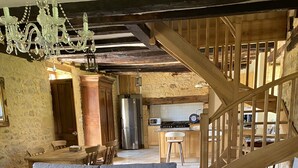 Una sala de estar acogedora con un sofá gris, una mesa de centro de madera y una escalera que da a una zona de cocina.