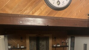 Una sala de estar acogedora con chimenea de piedra, muebles de madera y un reloj de pared grande.