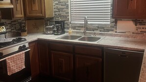 Una cocina con armarios de madera, encimera de granito, pileta de acero inoxidable, estufa y lavavajillas.
