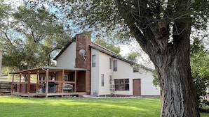 Una casa de dos pisos con un porche y un árbol grande en frente.