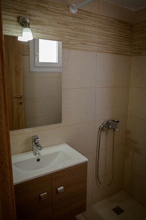 Ein Badezimmer mit Waschbecken, Spiegel, Dusche und Holzschrank.