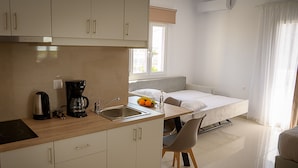 A compact kitchenette with a coffee maker, sink, and a small dining area with a chair. - Sunsea studios close to the beach- Mountain view studio 6 (Κάτω Γούβες)