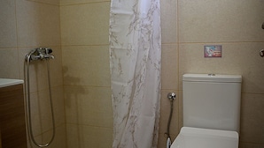 A small bathroom with a shower, toilet, and a hand dryer. - Sunsea studios close to the beach- Mountain view studio 6 (Κάτω Γούβες)
