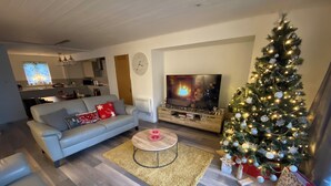 Una sala moderna con un sofá gris, una mesa de centro, un árbol de Navidad y un televisor.