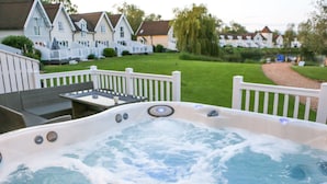 Un jacuzzi con vista a una cerca blanca de piquetes, una mesa de comedor y casas al fondo.