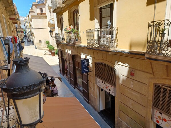 A narrow street with buildings, a pizzeria, and a gelato shop.