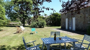 A patio with a table and chairs, a bottle of wine, and a bowl of fruit.